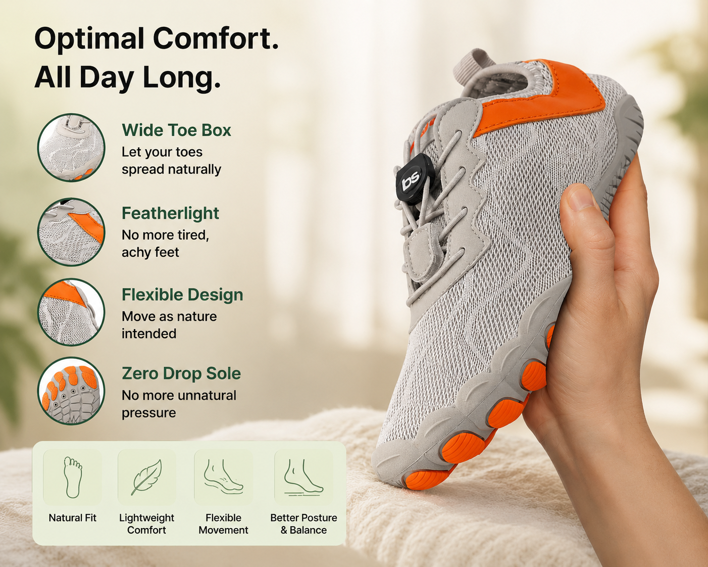 A hand holds a gray and orange athletic shoe.